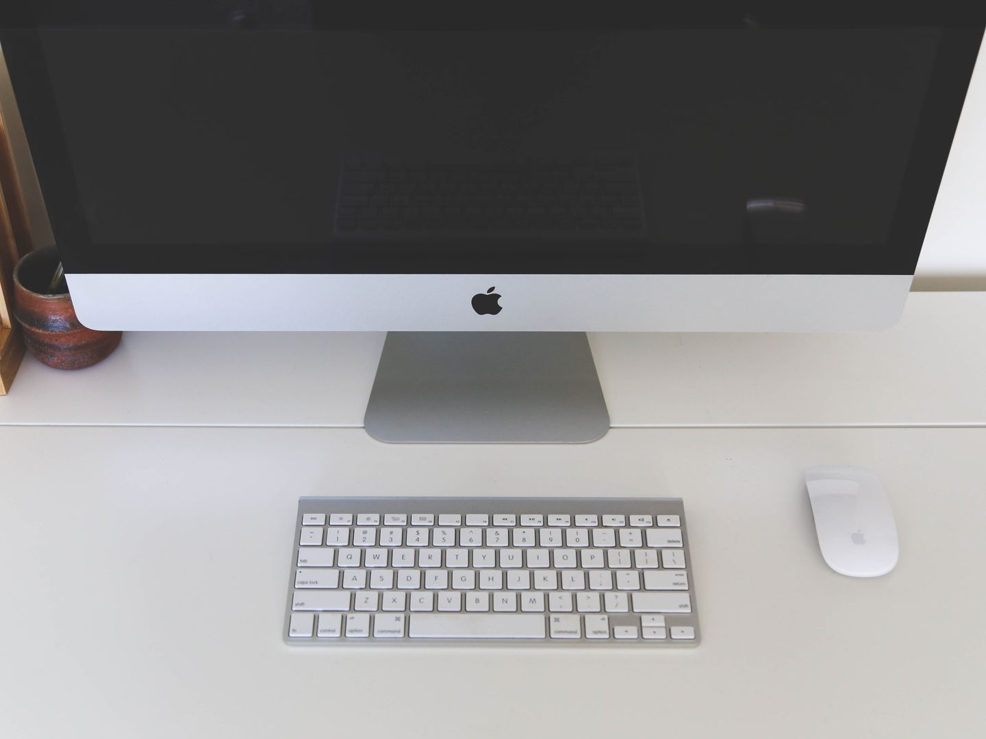 Minimalist home office workspace featuring a desktop computer, keyboard, and mouse on a white desk.