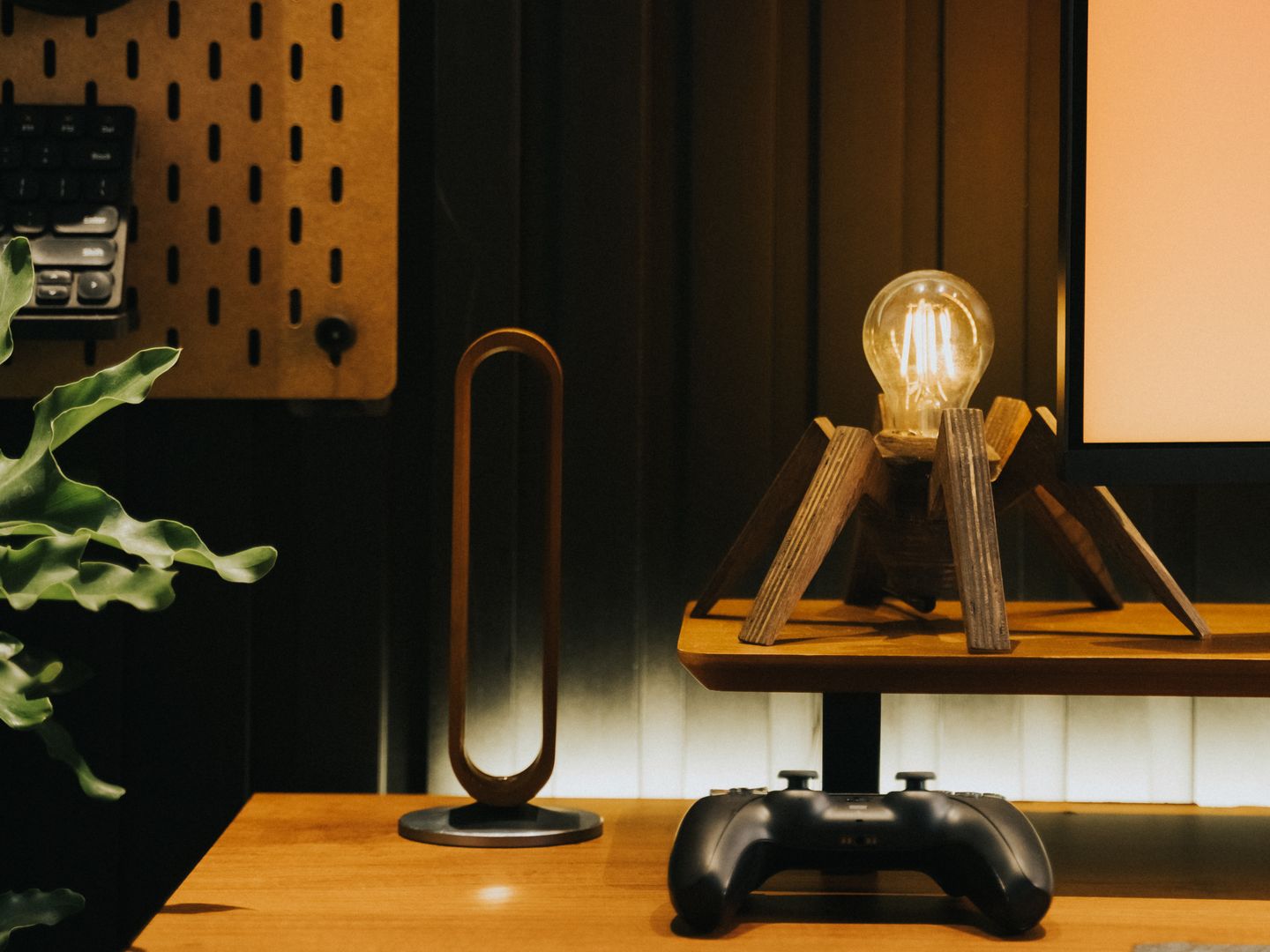 Stylish desk setup featuring a unique lamp, game controller, and plant for a contemporary workspace.